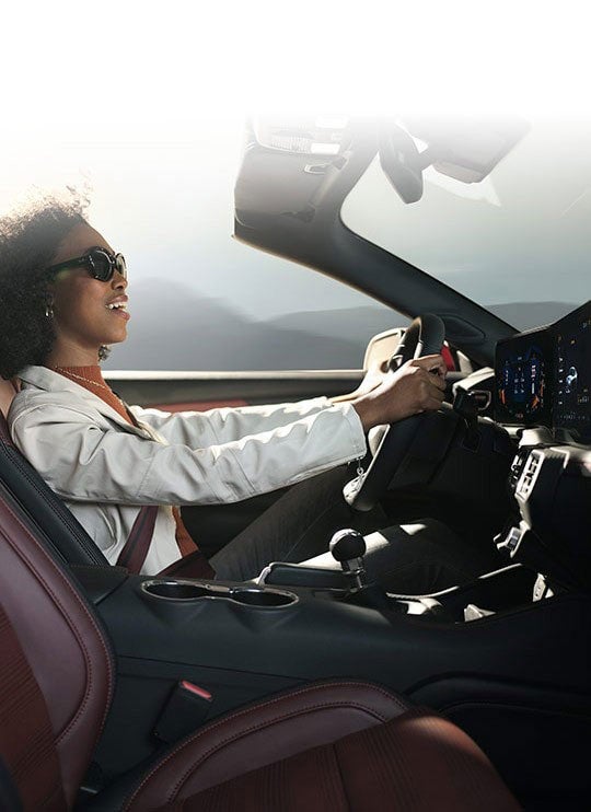 Person sitting in the driver’s seat of a 2024 Ford Mustang® convertible | Pfeifle Ford in Wishek ND